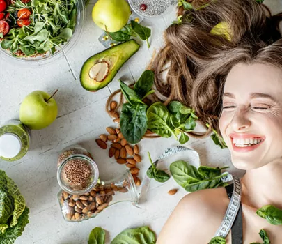 Porträt einer Frau, umgeben von verschiedenen gesunden Lebensmitteln auf dem Boden liegend