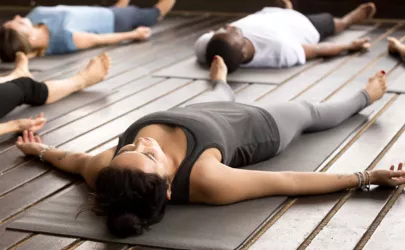 Gruppe sportlicher Menschen, die eine Yogastunde im Liegen praktizieren