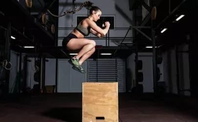 Junge starke Frau macht Box Jump im Fitnessstudio