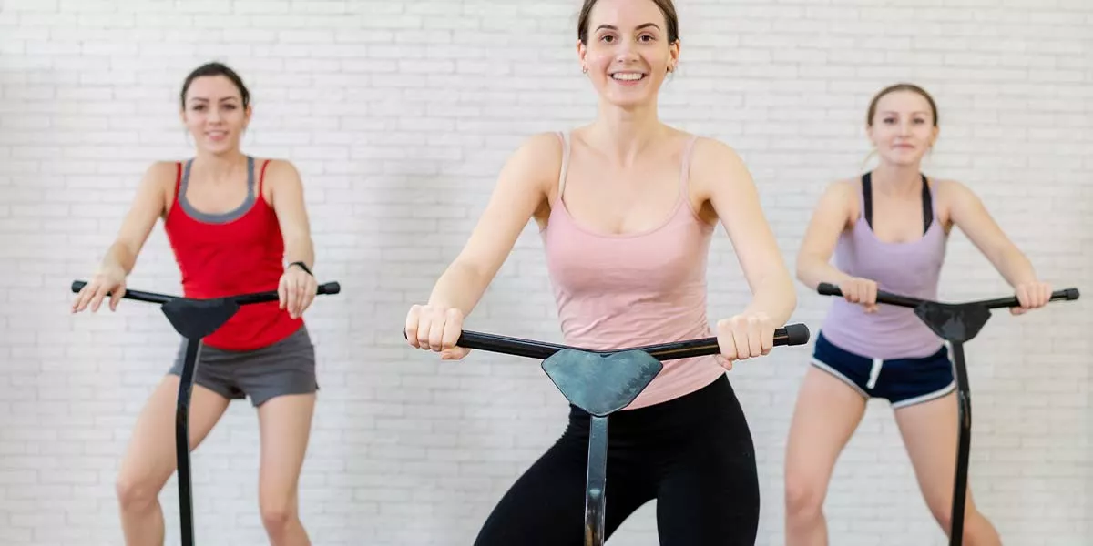 In einem hellen Raum sind drei junge Frauen zu sehen, die gerade mit dem Minitrampolin trainieren. Ihr Blick wirkt freudig und ist in die Kamera gerichtet