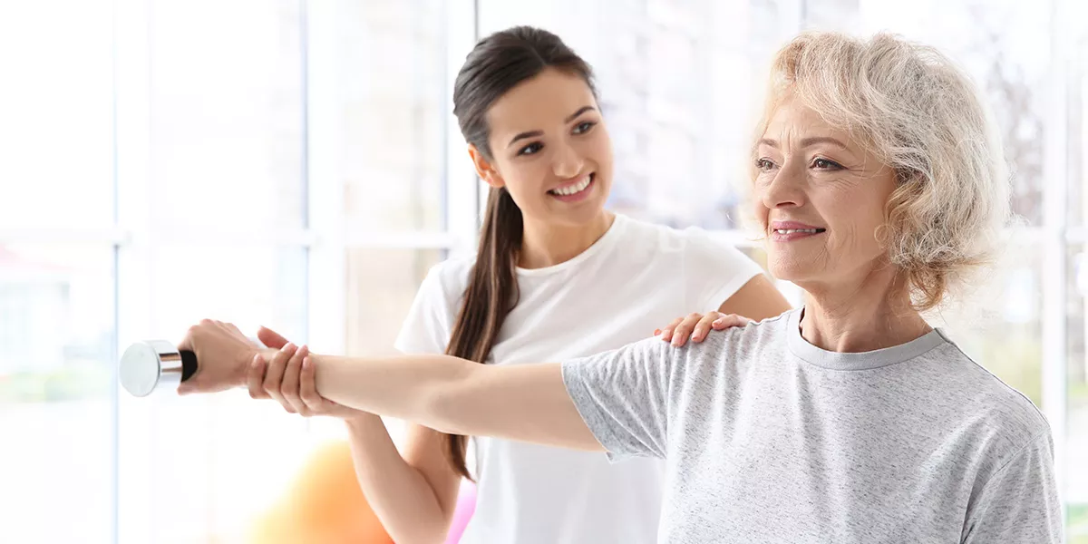 Physiotherapeutin macht eine Übung mit einer älteren Patienten