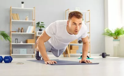 Ein Mann macht Push Ups in seinem hellen Wohnzimmer