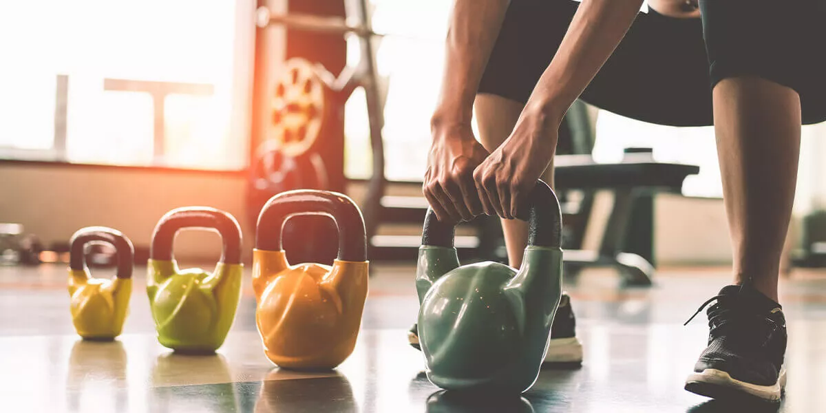 Eine Person nimmt einen Kettleball in beide Hände