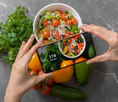 Handy mit dem ein Foto von Essen gemacht wird, auf dem die Kalorienzahl erscheint