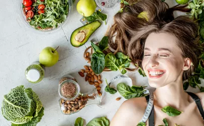 Porträt einer Frau, umgeben von verschiedenen gesunden Lebensmitteln auf dem Boden liegend