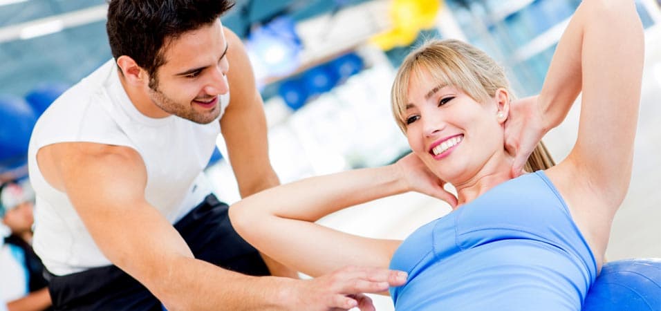 eine Frau bei einer Fitnessübung und ein Trainer, der Anweisungen gibt, Trainerschein Fitness, Fitnesstrainer werden